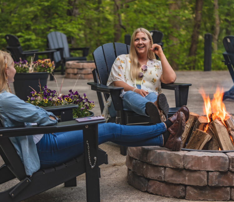 Two women sitting around a campfire